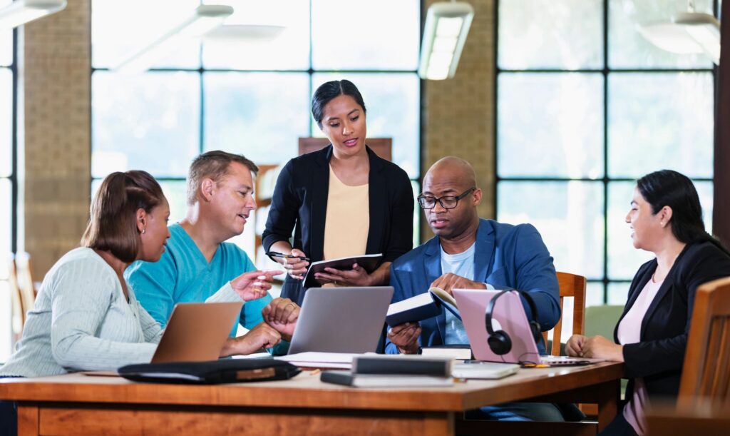 Multiracial group working on project with books, laptops
