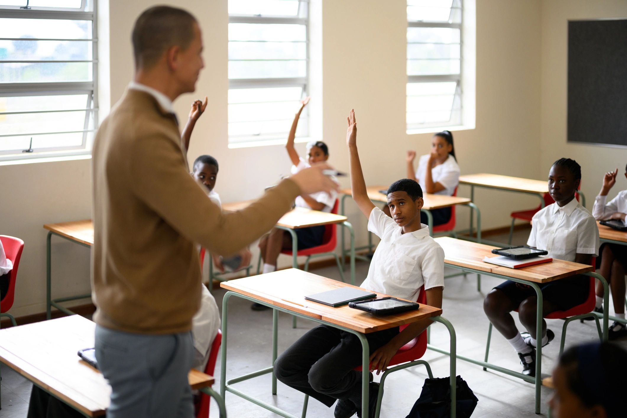 Schoolchildren in class with hands raised and engaged in learning